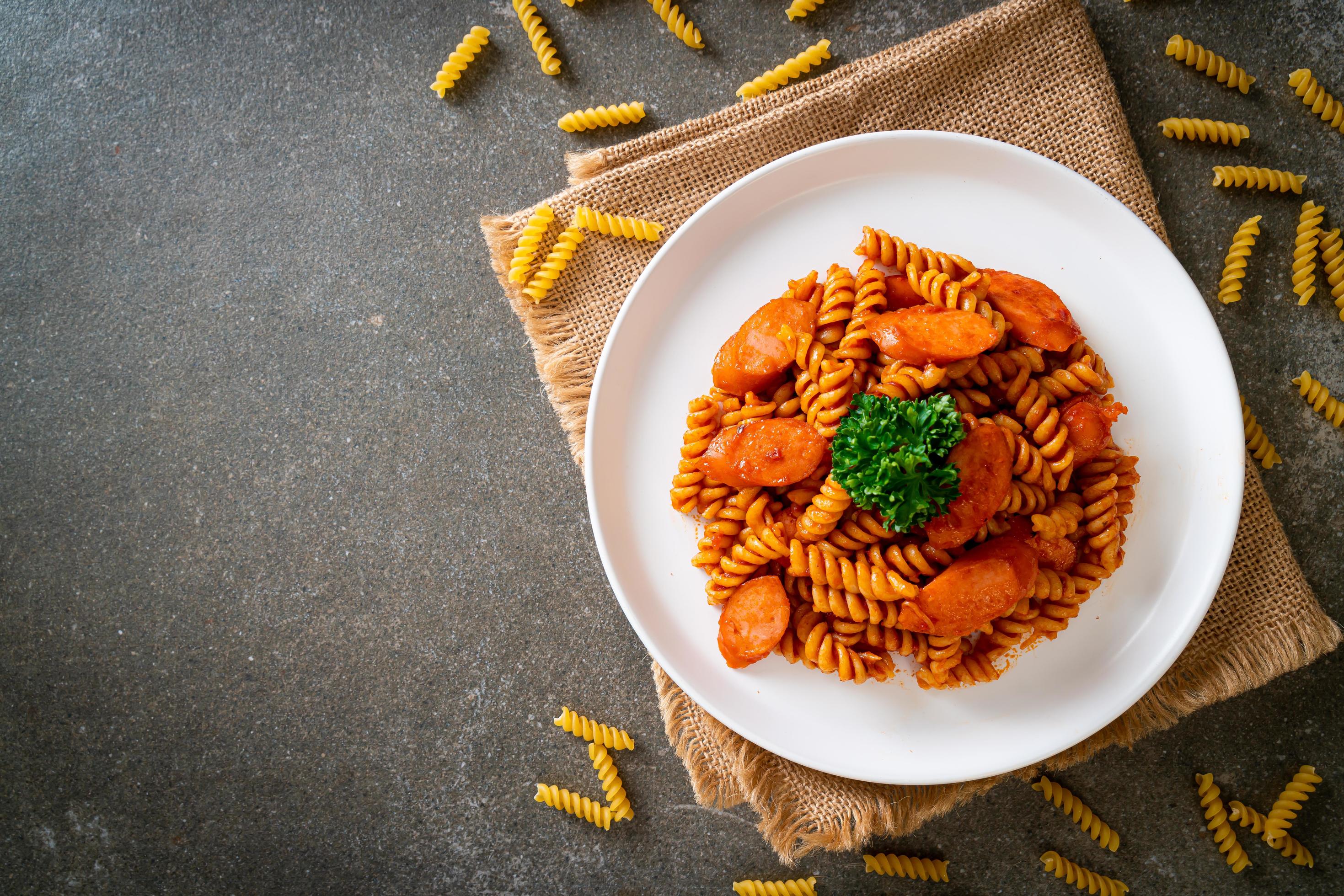 Spiral or spirali pasta with tomato sauce and sausage – Italian food style Stock Free