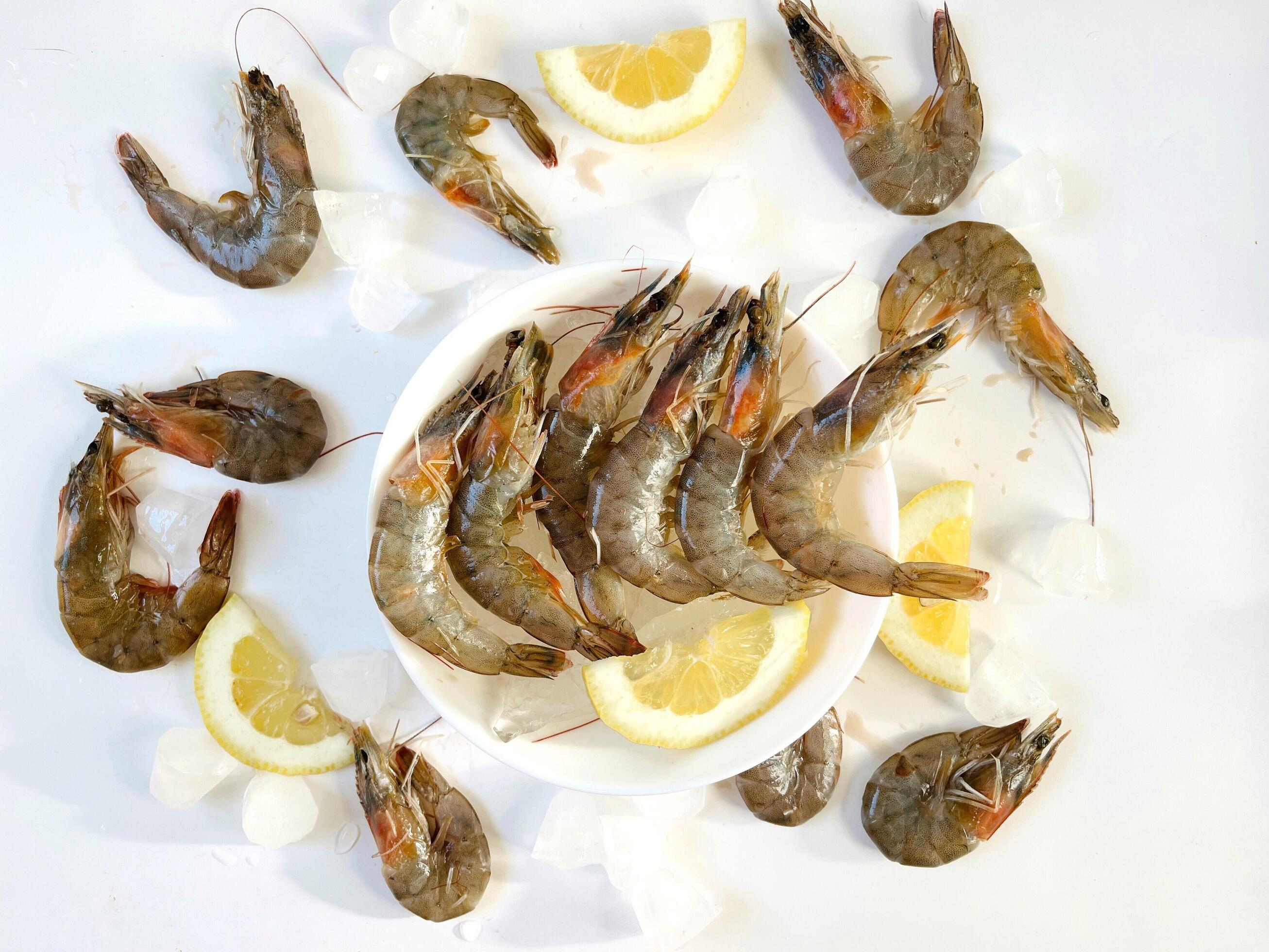 Healthy food. Fresh shrimps with ice and lemon on plate on white background top view Stock Free