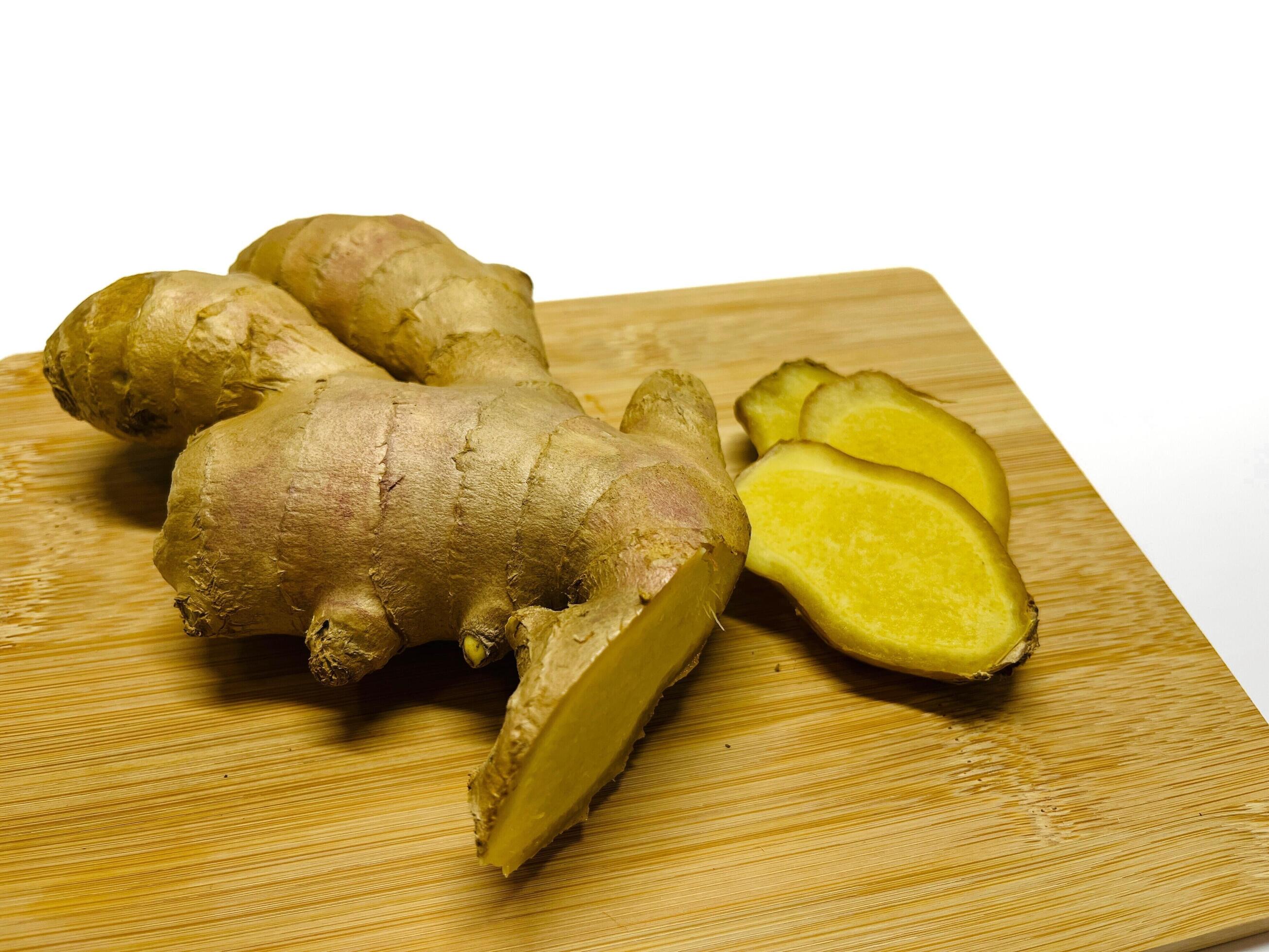 Ginger root with sliced on wooden cutting board on white background Stock Free