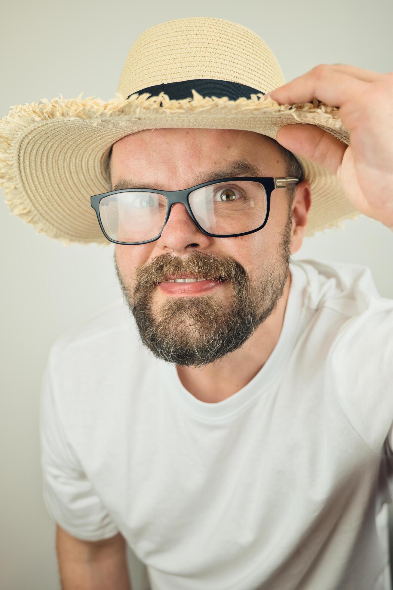 portrait of handsome bearded man with straw hat and glasses smiling, wearing white shirt , isolated on white background Stock Free