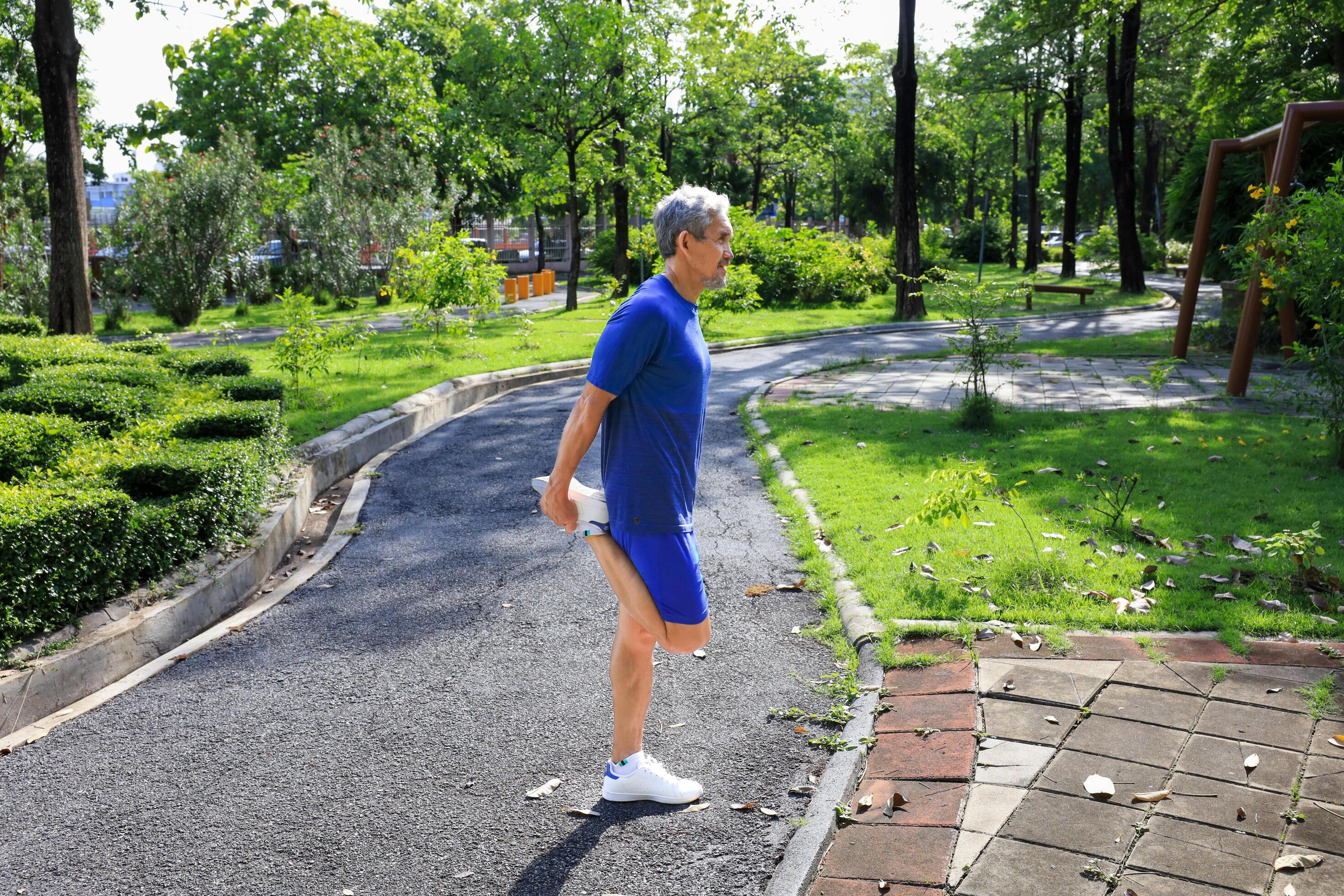 Senior Asian man is stretching his leg muscle during warm up exercise work out in the morning at public park for healthy and longevity concept Stock Free