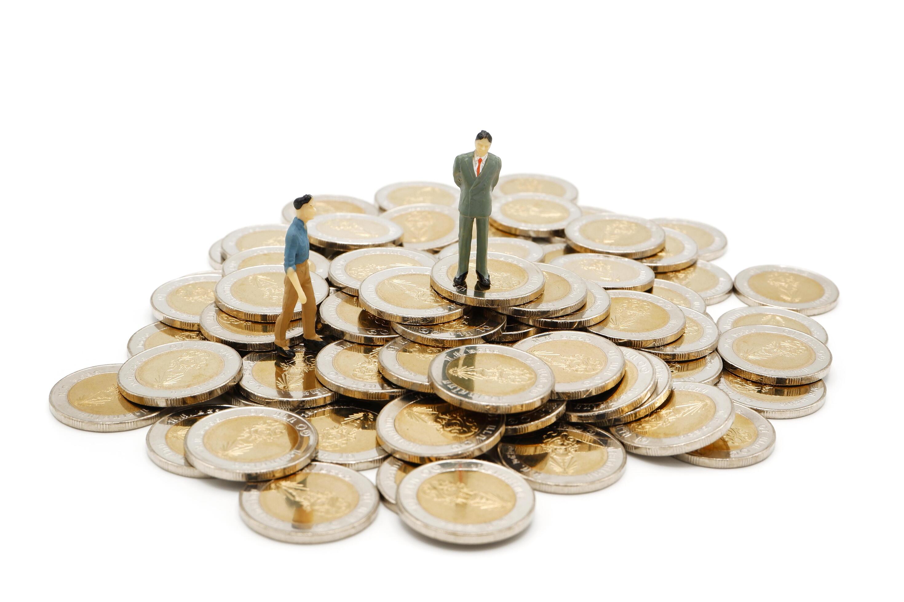 Miniature businessman standing on pile of new 10 Thai Baht coins, isolated on white background. Business concept. Stock Free