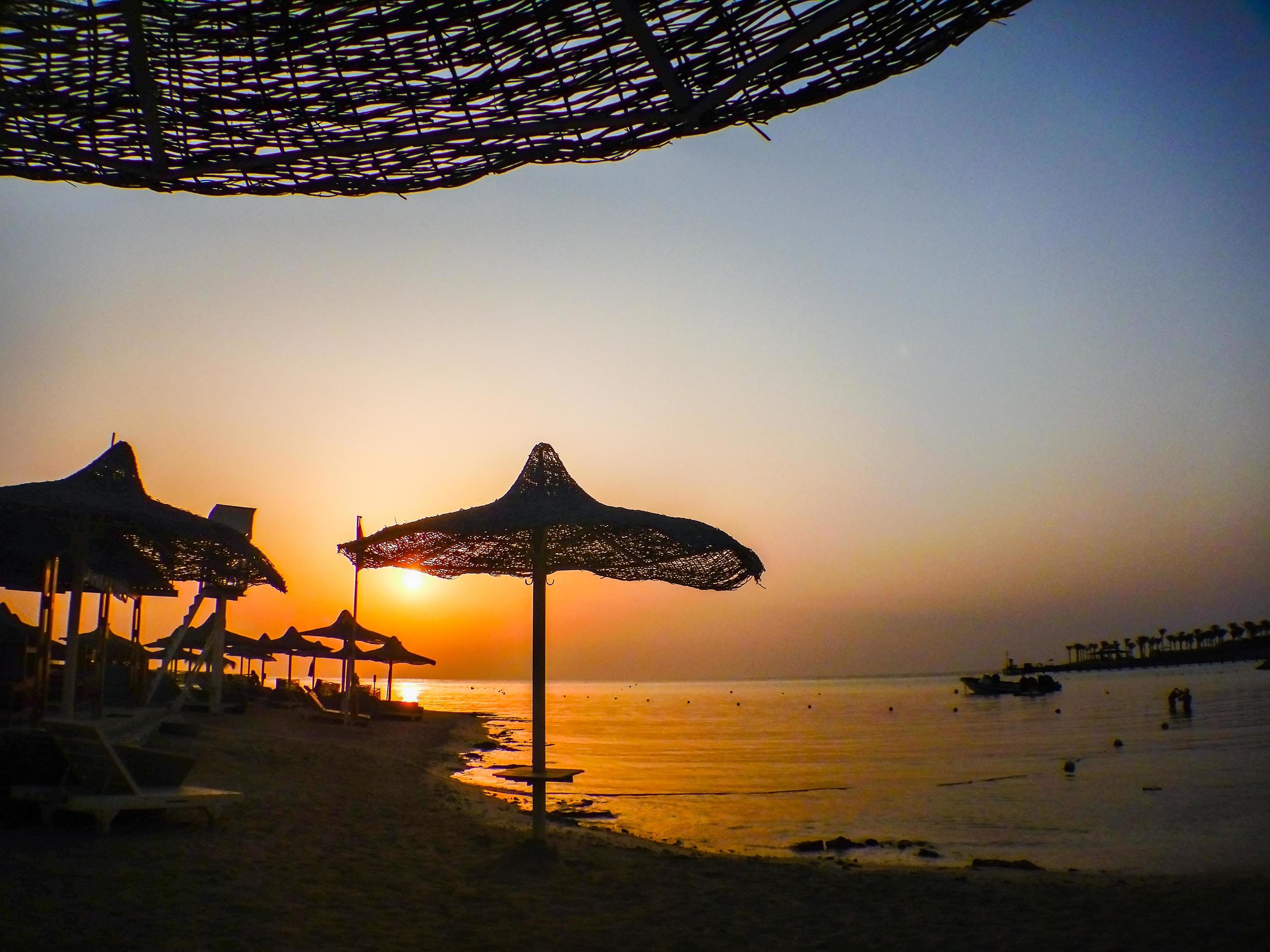 amazing sunset on the beach with sun umbrellas Stock Free