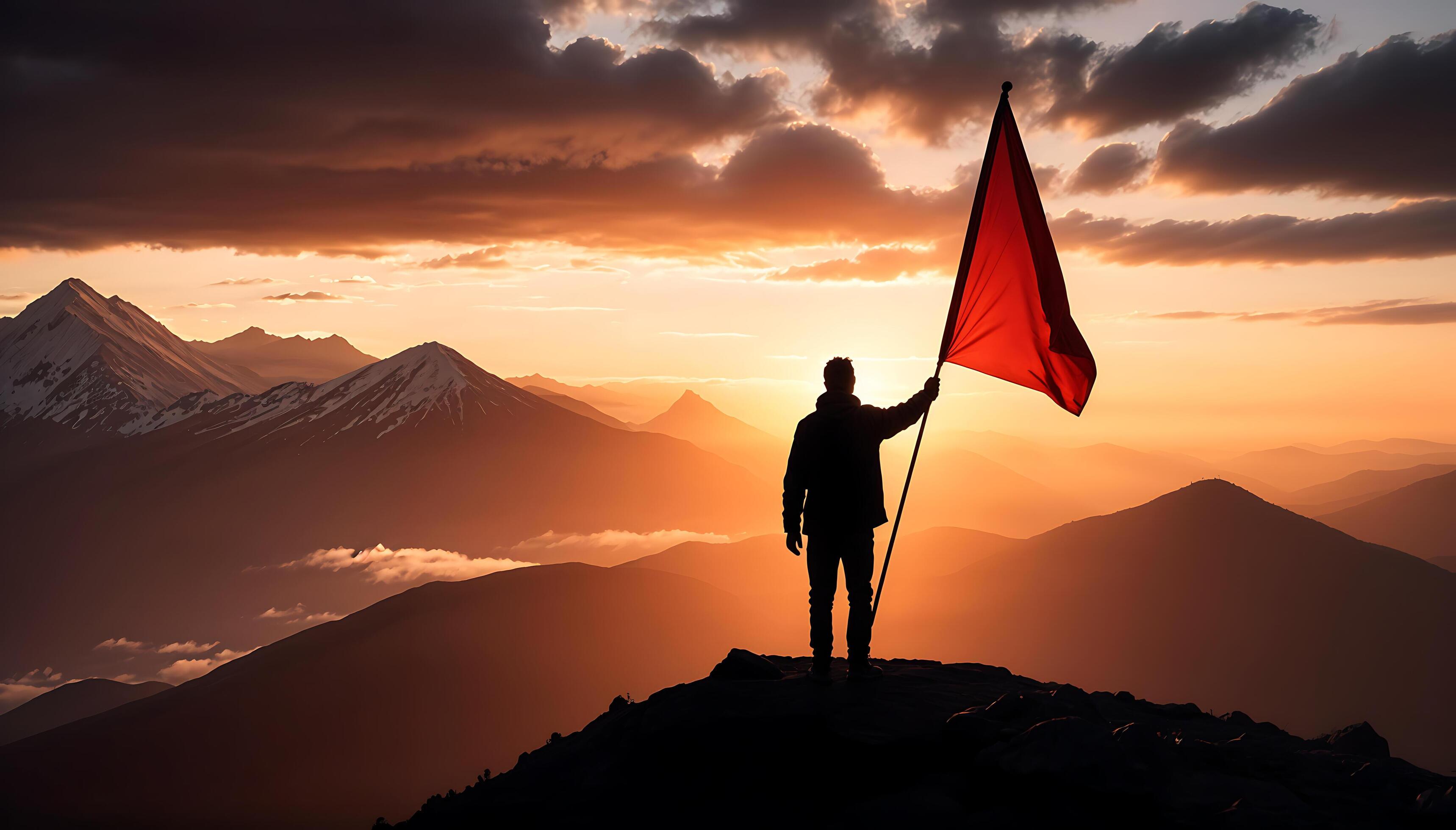 Goal concept a silhouette photo of a person holding a red flag on a mountain peak Stock Free