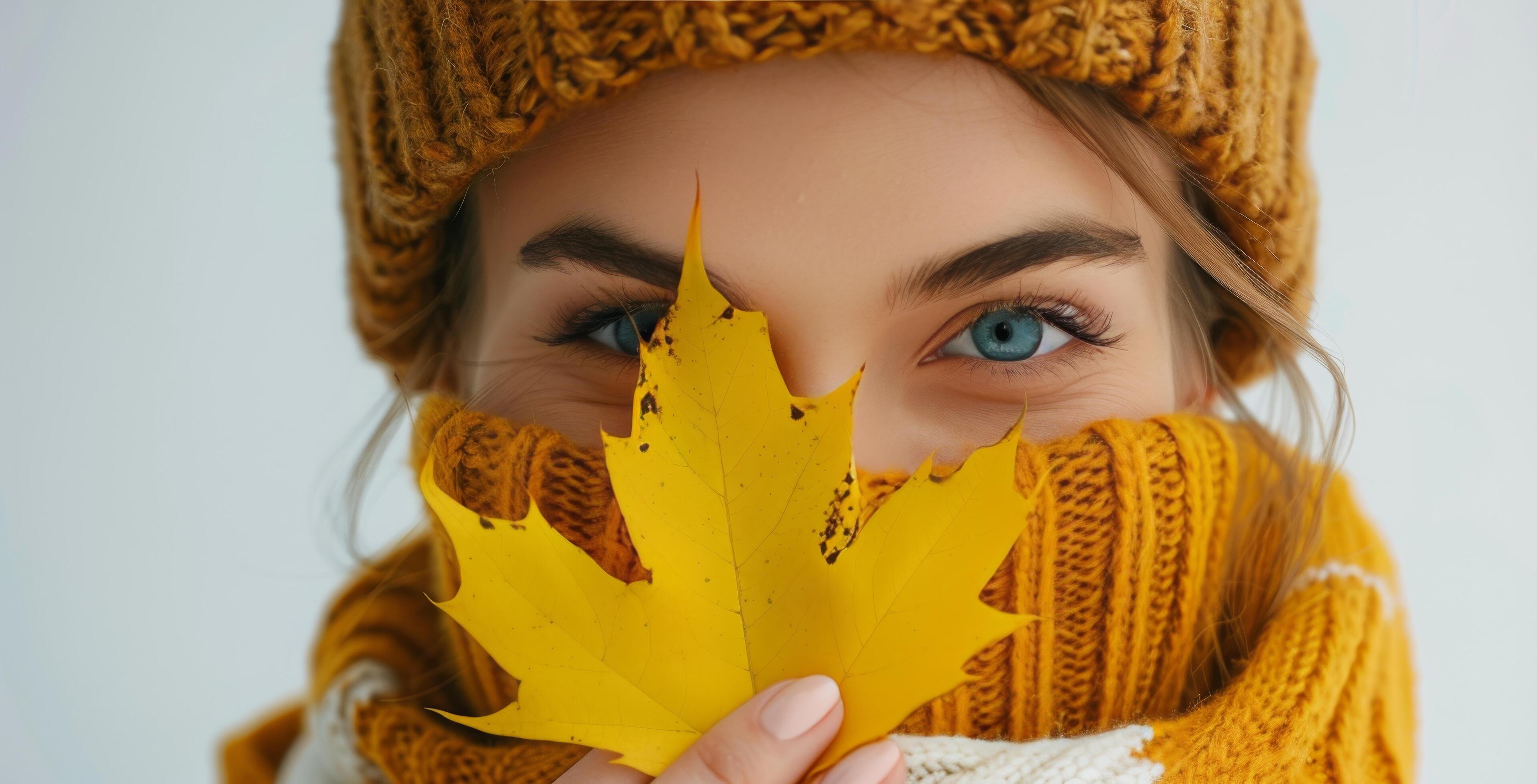 Woman Wearing Yellow Hat and Sweater Holding a Fall Leaf Stock Free