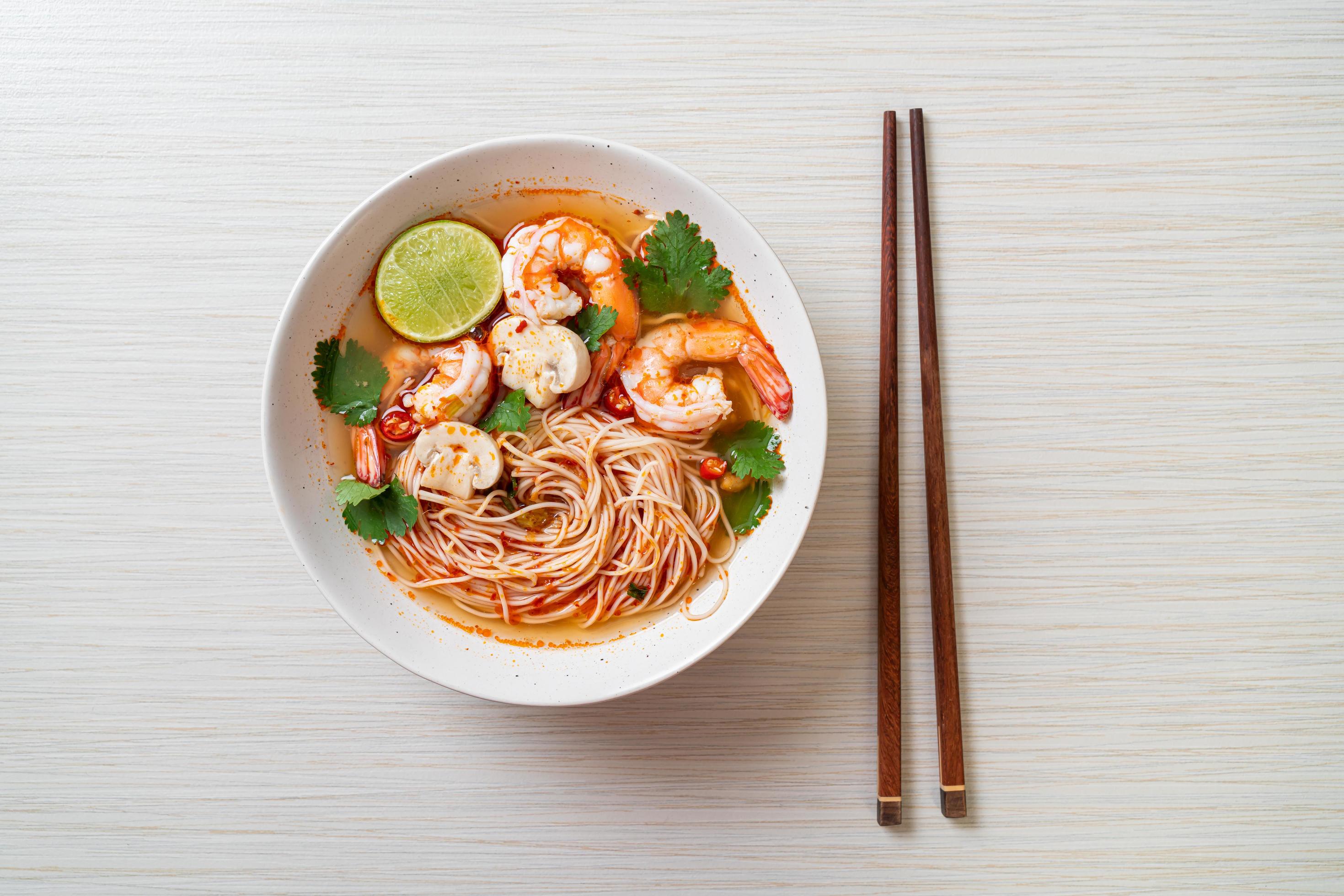 Noodles with spicy soup and shrimps in white bowl, or Tom Yum Kung – Asian food style Stock Free