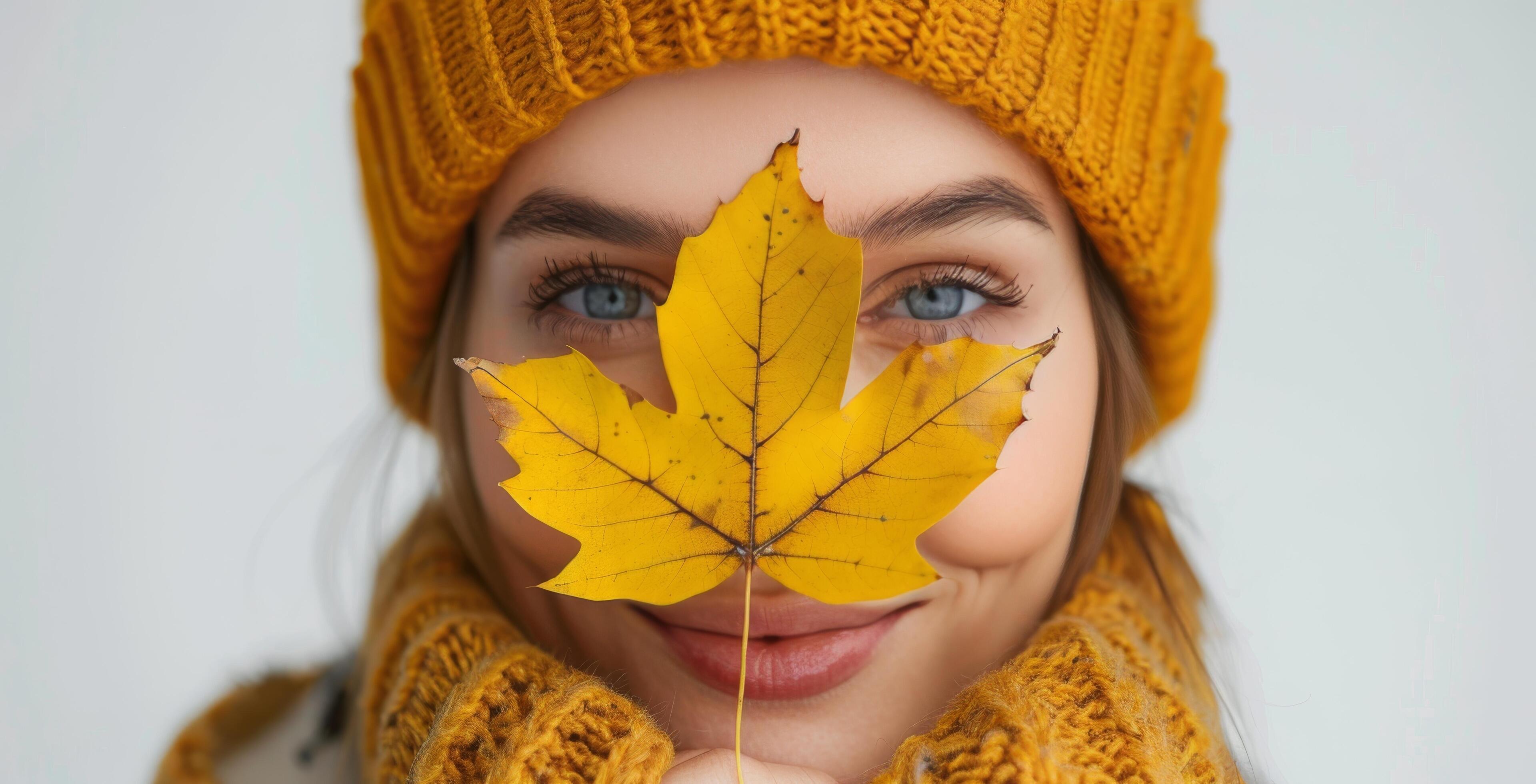 Woman Wearing Yellow Hat and Sweater Holding a Fall Leaf Stock Free