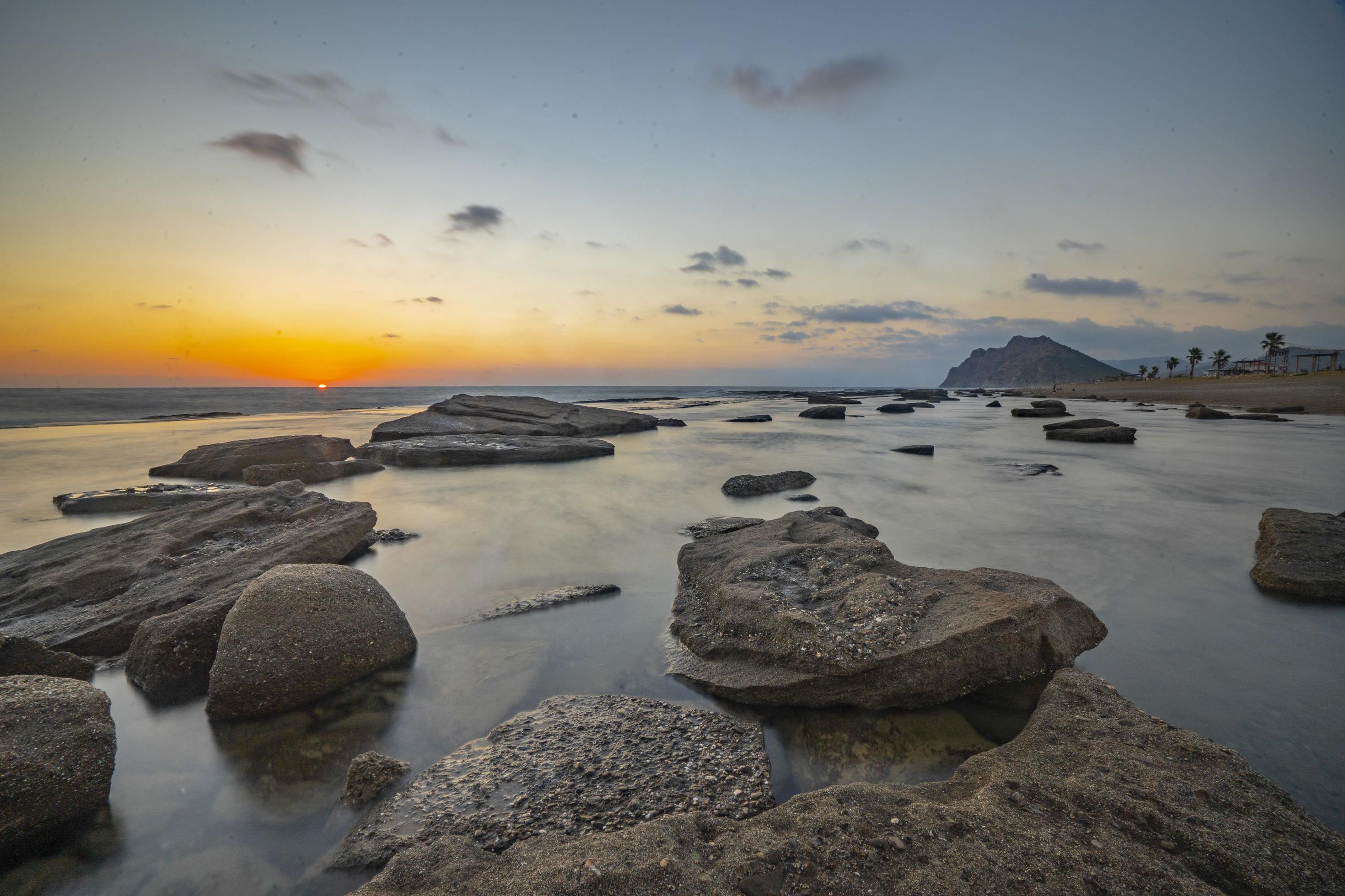 Long exposure photography of waves and pebbles on Beach in the sunset Stock Free