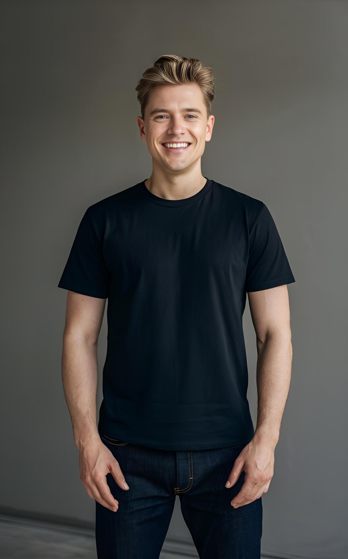 A portrait of a man in a black t-shirt and jeans, standing against a neutral grey background. Stock Free