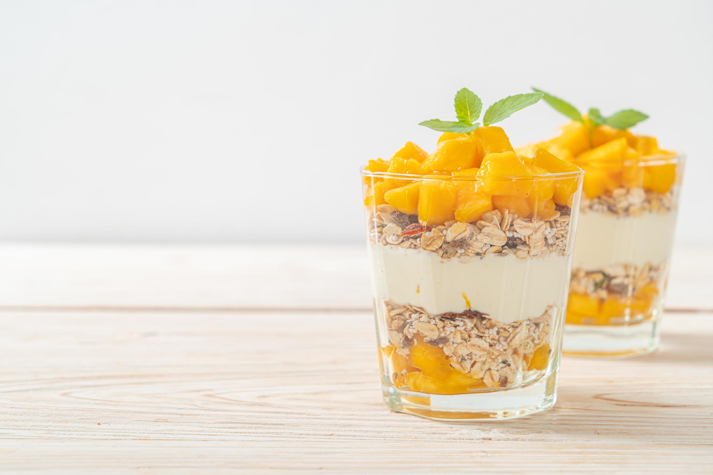 Fresh mango yogurt with granola in glass – healthy food style Stock Free