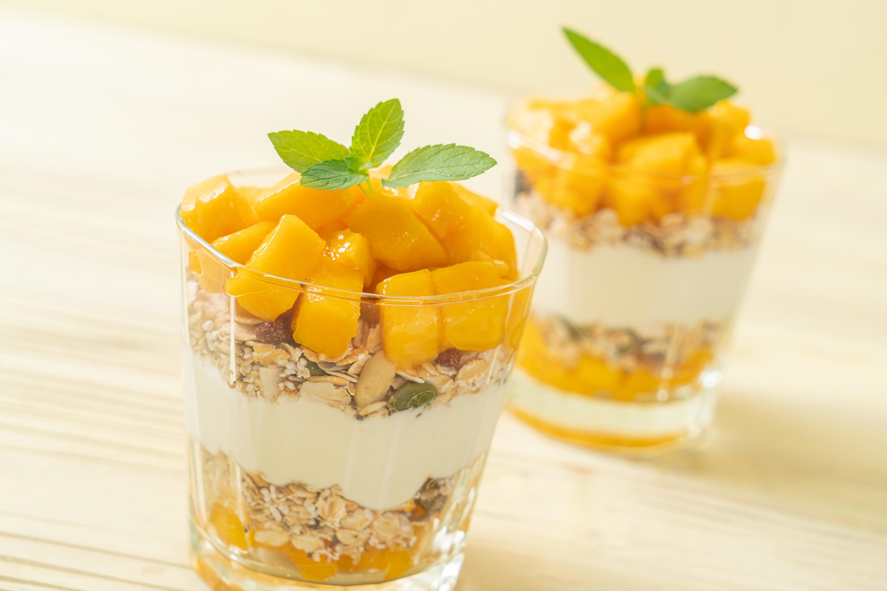 Fresh mango yogurt with granola in glass – healthy food style Stock Free