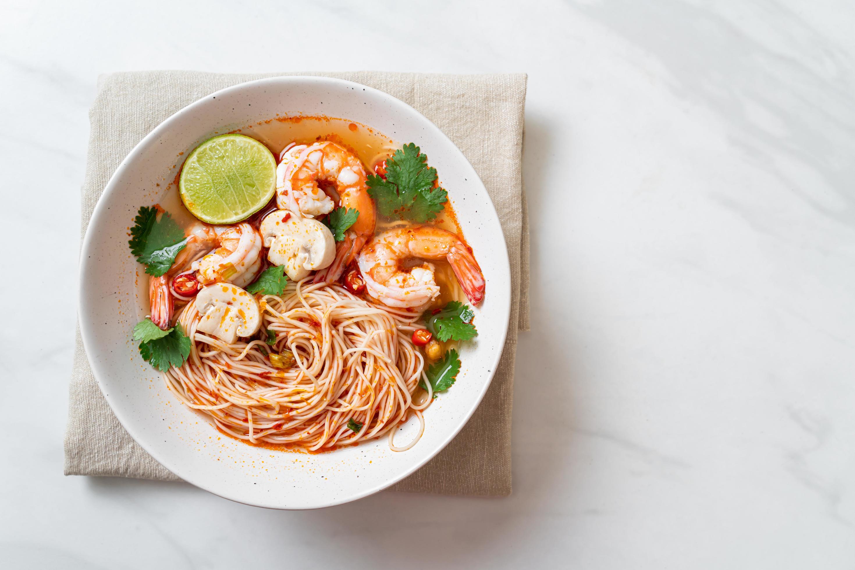 Noodles with spicy soup and shrimps in white bowl, or Tom Yum Kung – Asian food style Stock Free