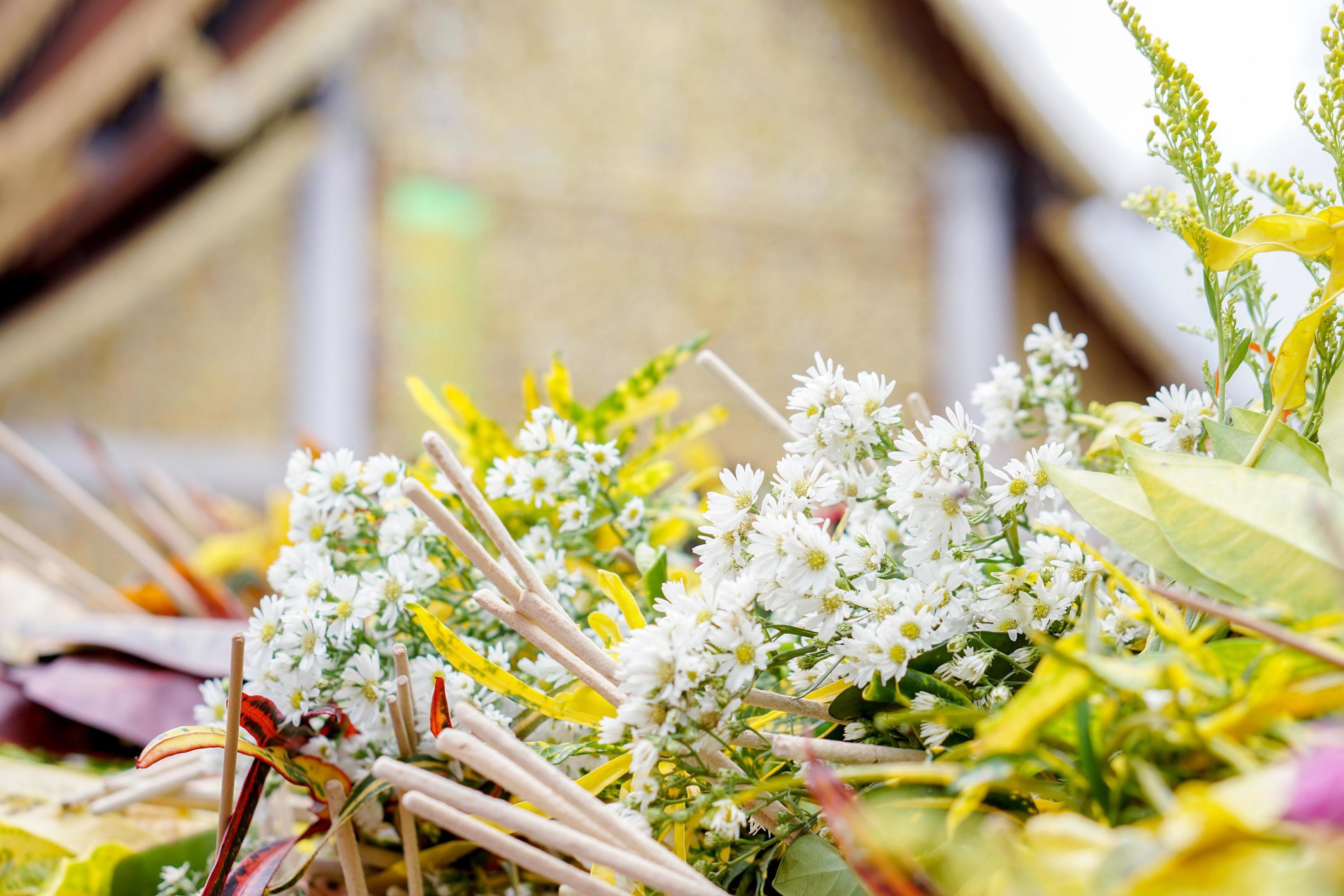 Closeup and crops heap of fragrant flowers with incense for worship the Buddha on blurry Thai temple sanctuary and blue background. Stock Free