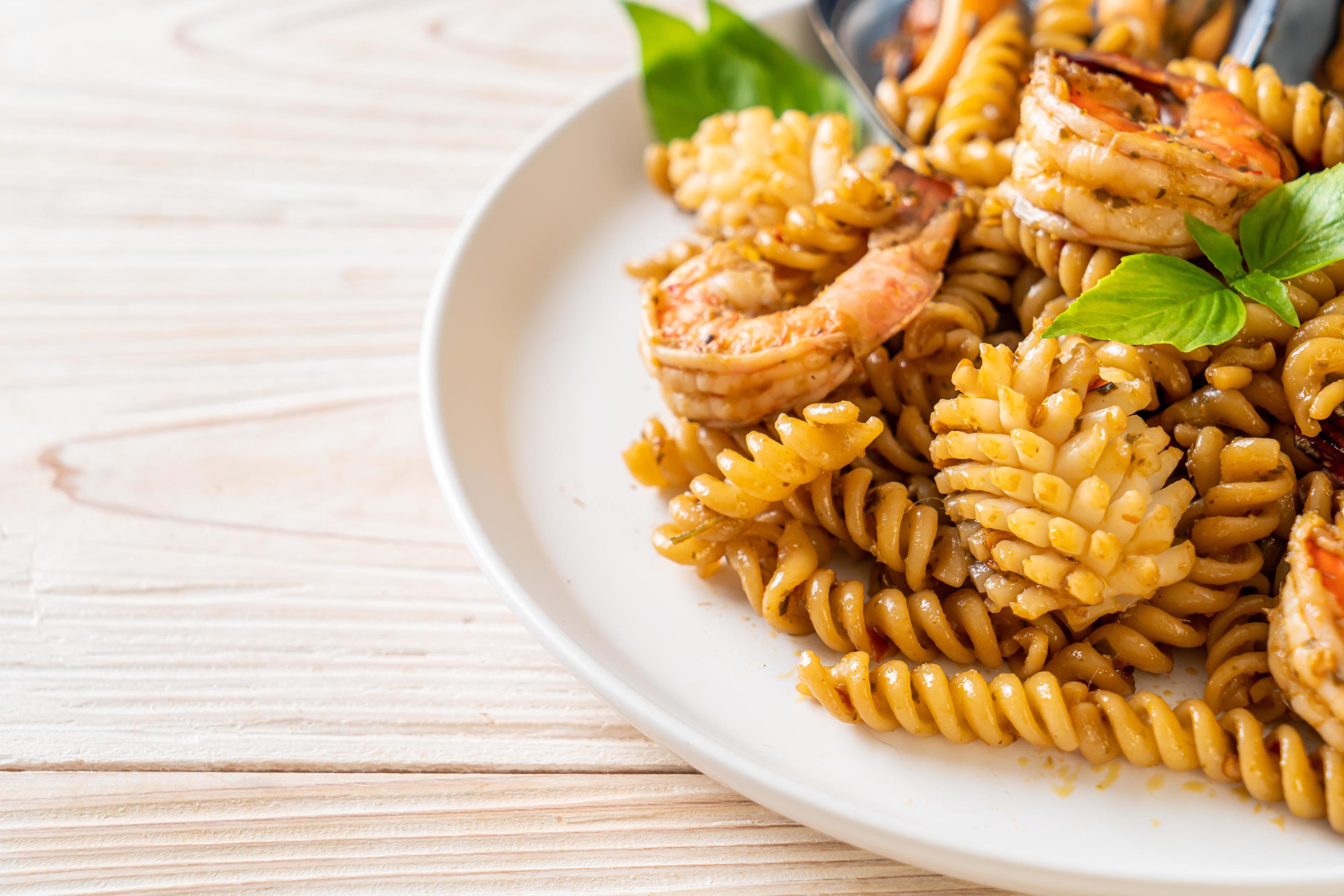 Stir-fried spiral pasta with seafood and basil sauce – fusion food style Stock Free