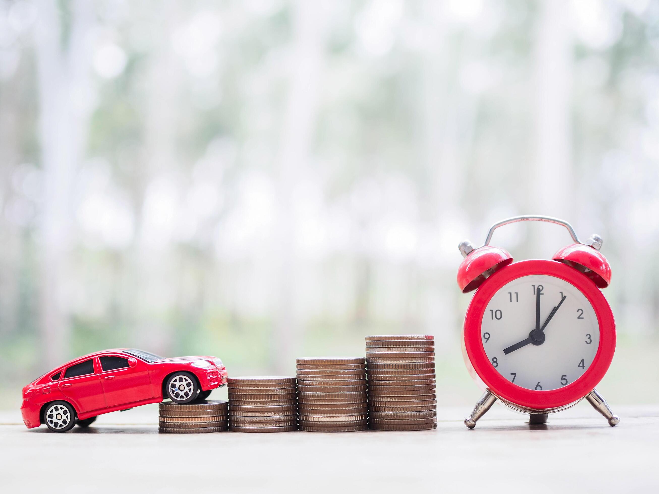 Toy car, stack of coins and red alarm clock. The concept of saving money and manage to success transport business Stock Free