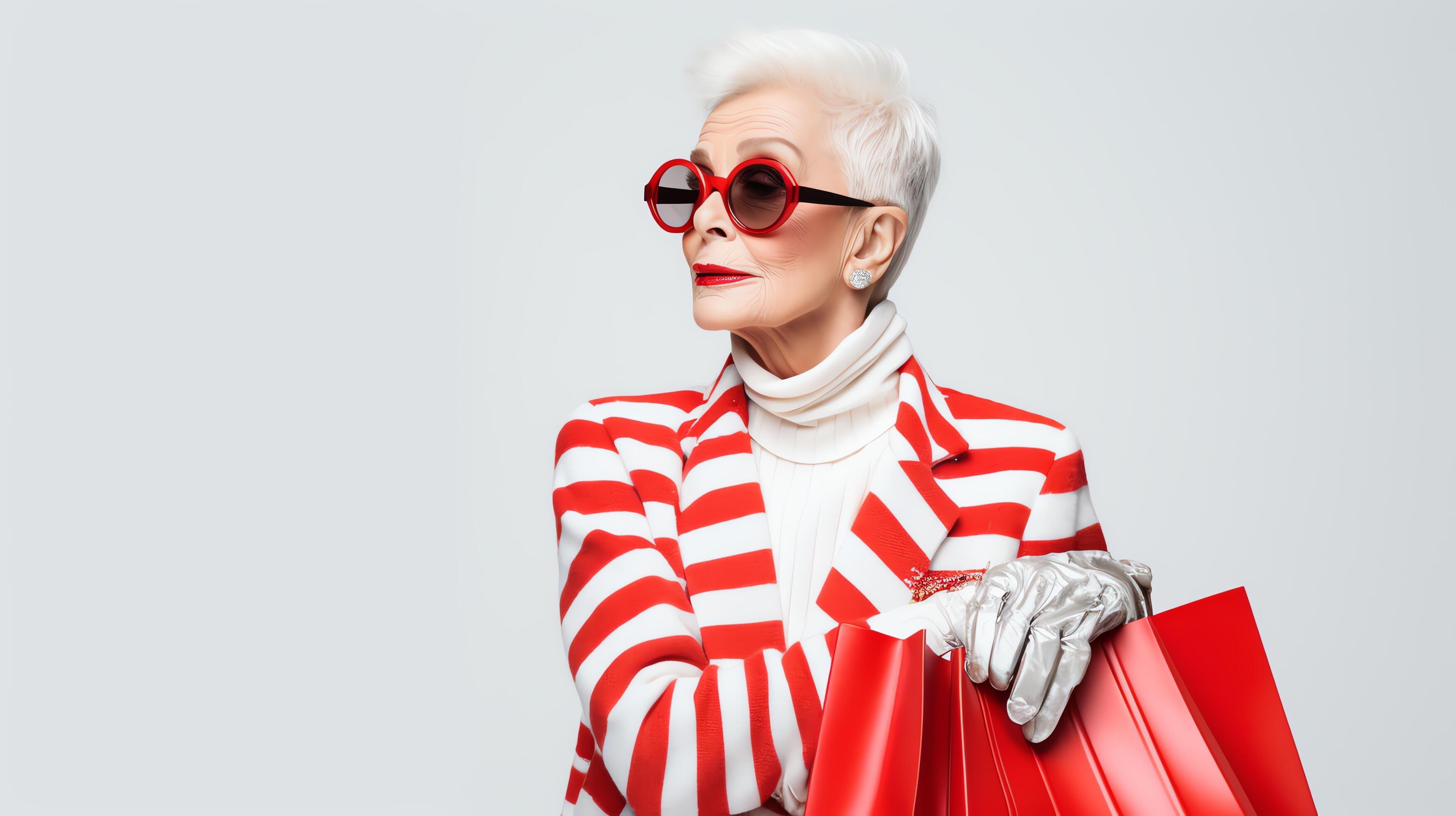 A stylish senior woman with short white hair and red sunglasses is wearing a red and white striped blazer Stock Free