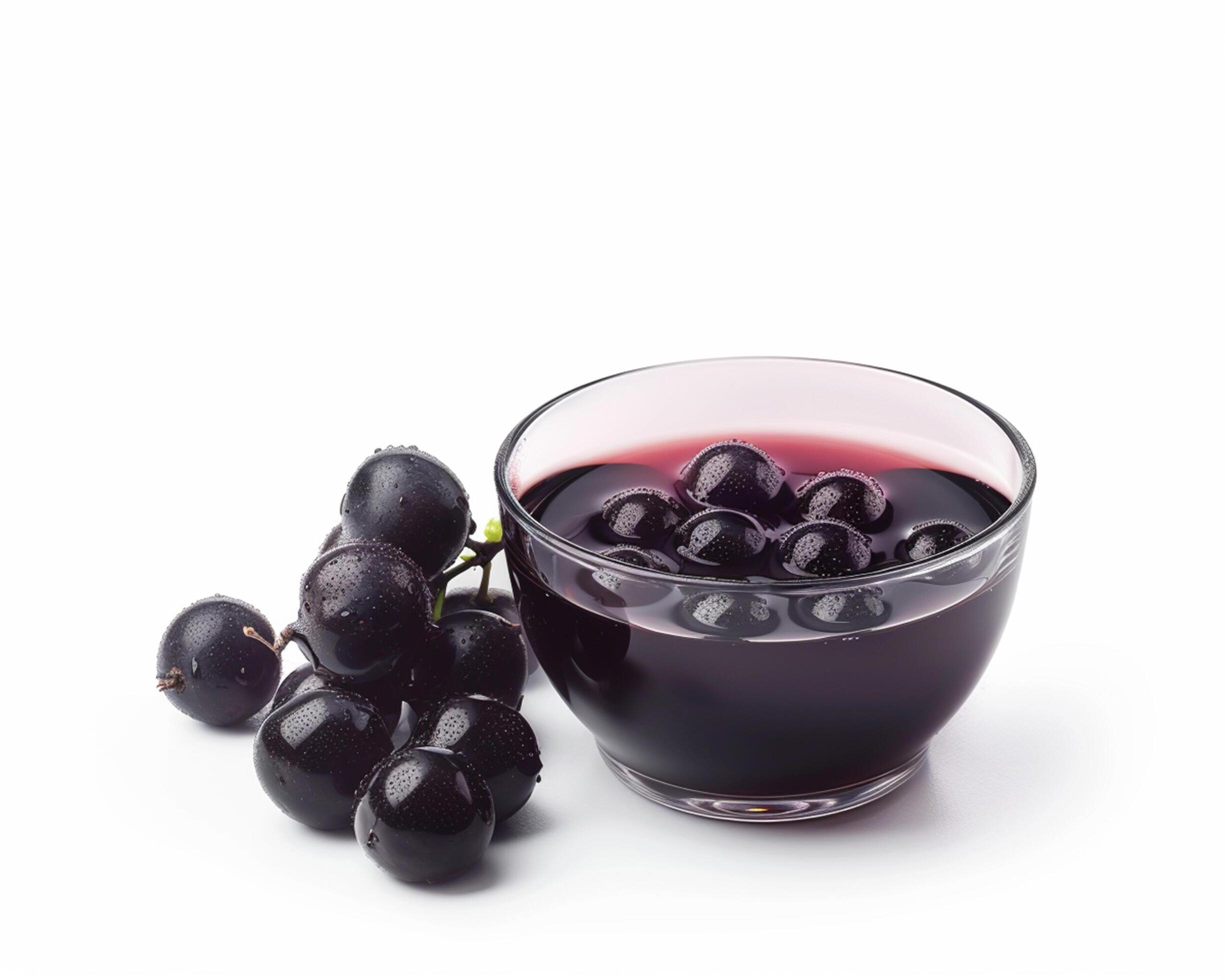 a glass bowl filled with black grapes and a bunch of grapes Stock Free