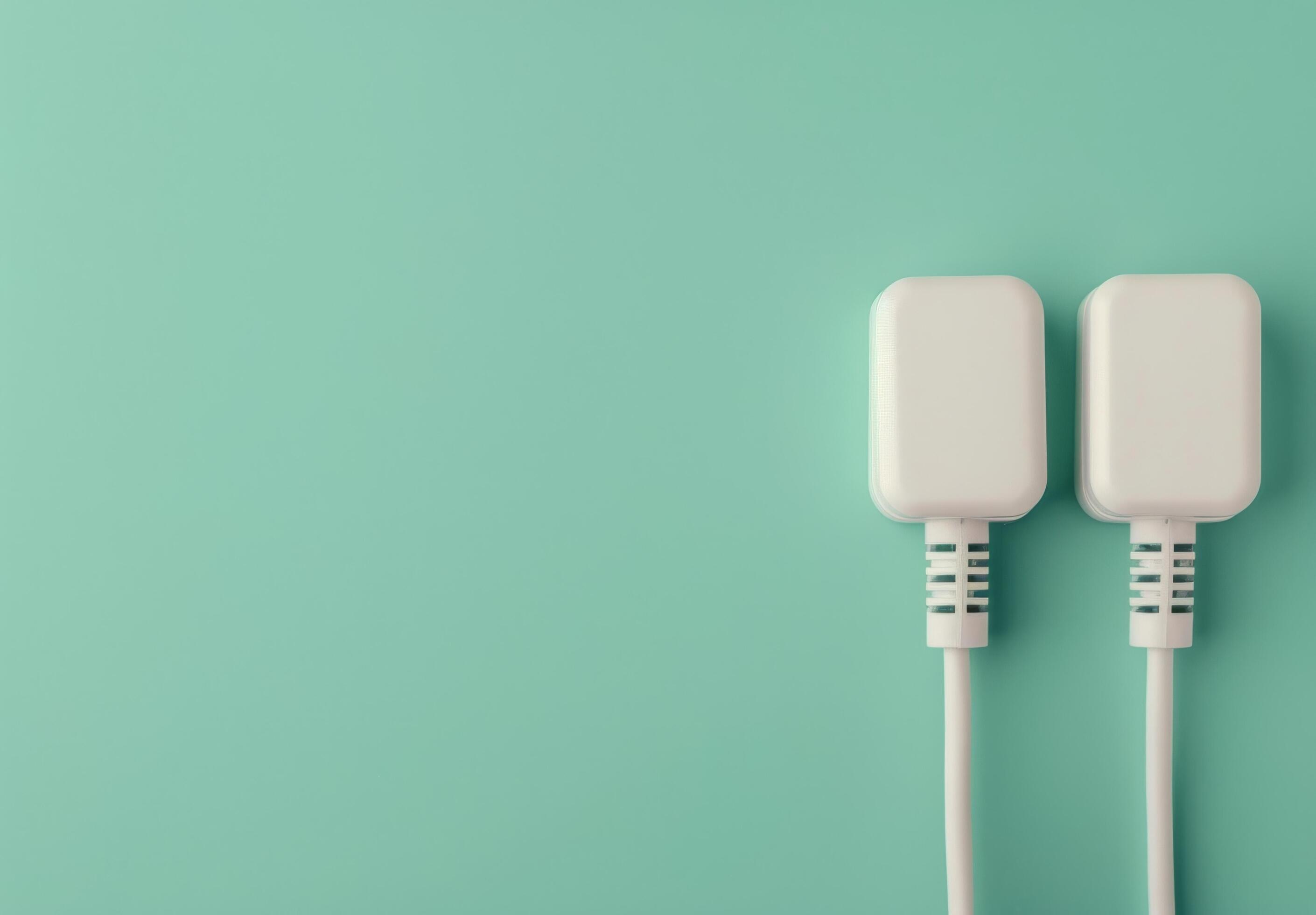 Two White Electrical Plugs on Teal Background Stock Free