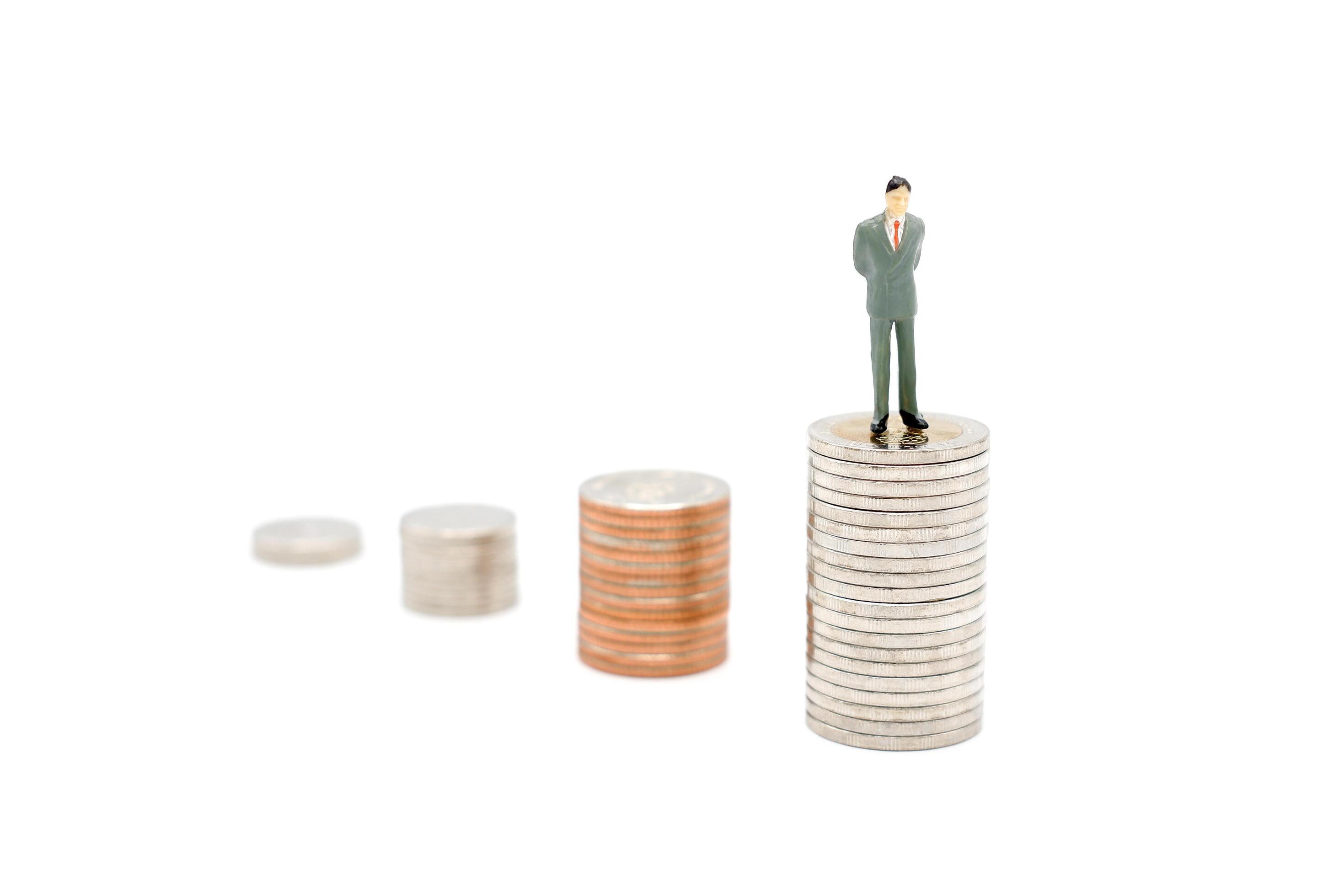 Miniature businessman standing on stack of new Thai Baht coins, isolated on white background. Business and finance concept. Stock Free