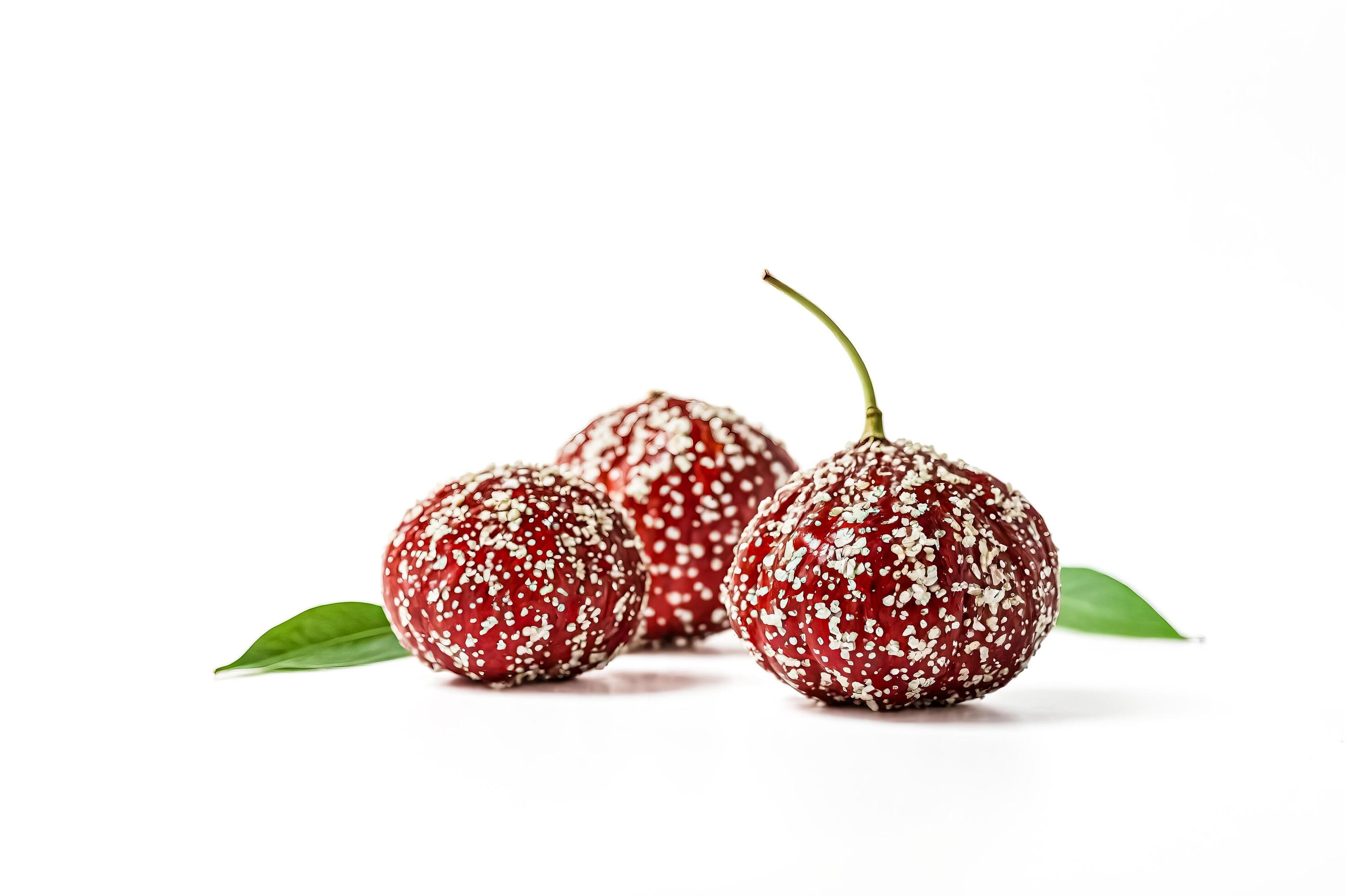 Close up of red fruits with white speckles and green leaves on white background Stock Free