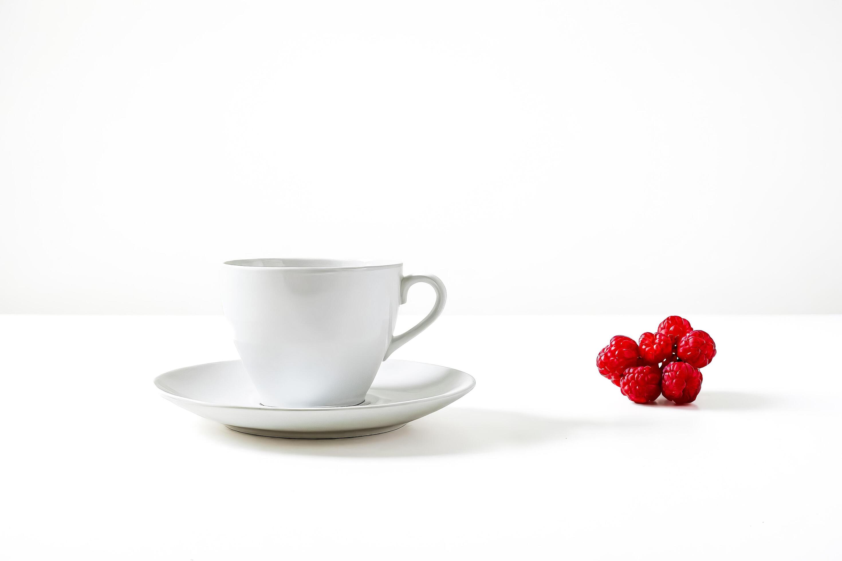 White Cup and Saucer with Red Raspberries on a White Background Stock Free