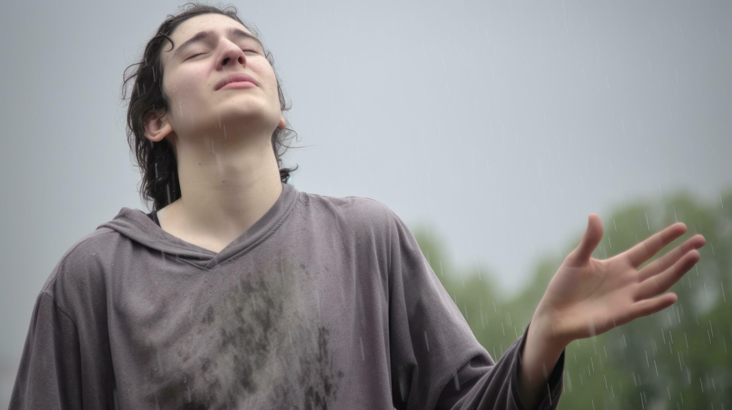 A young man stands in the rain, with his hands open, enjoying the moment. Generative AI Free Photo