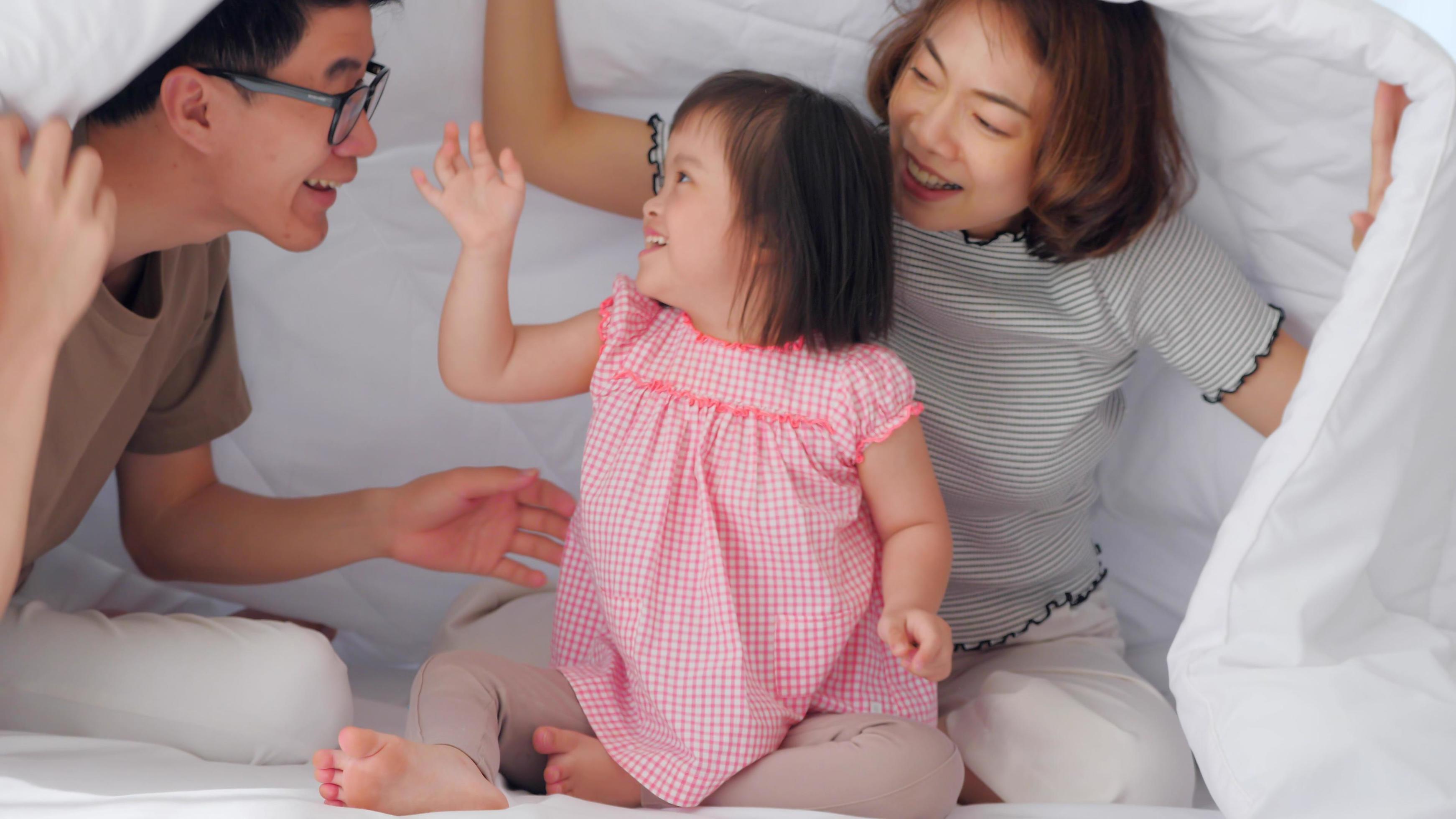 Happy family with mother, father and disabled daughter spending time together in bedroom. Stock Free