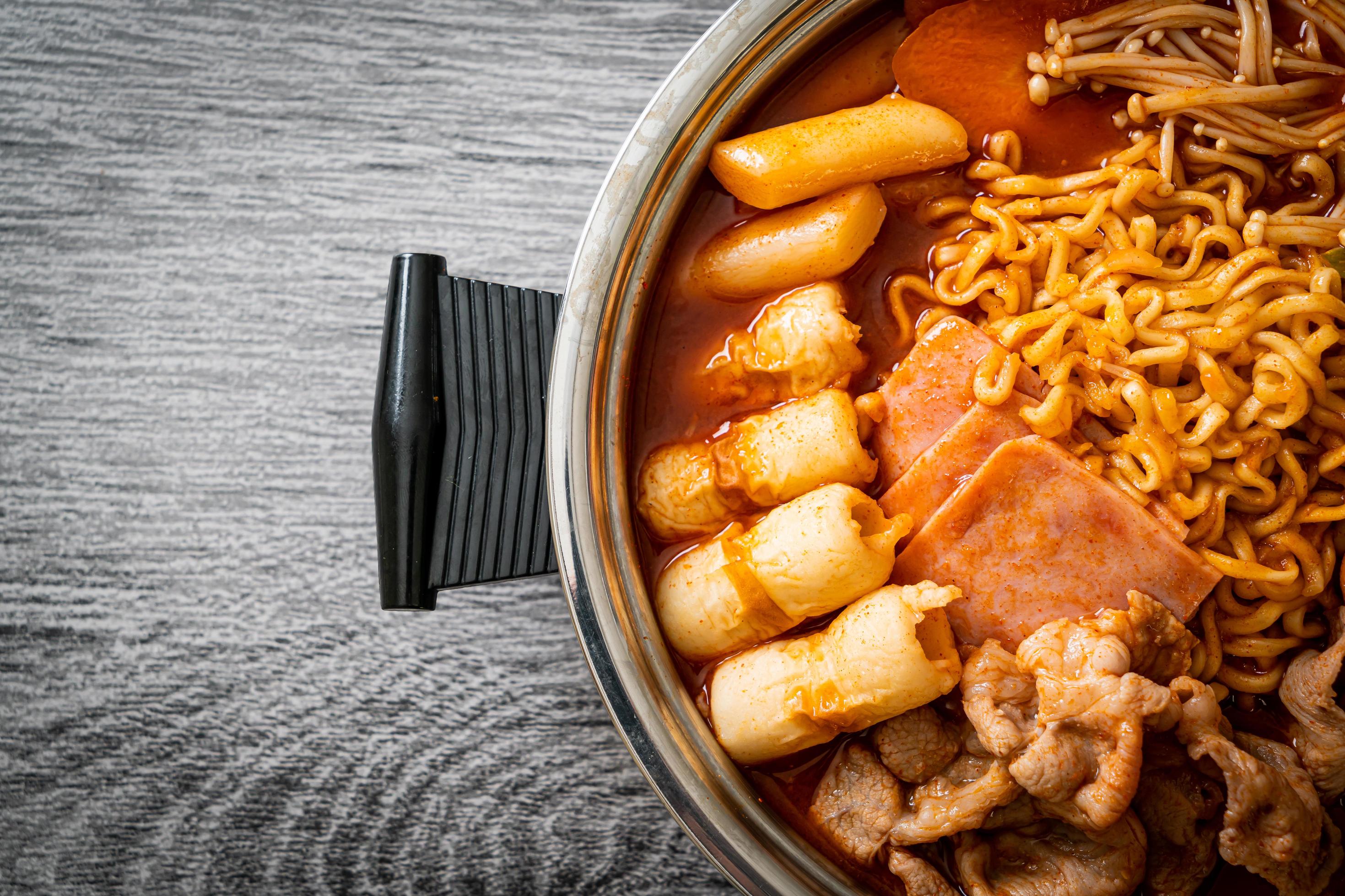 Budae Jjigae or Budaejjigae, Army stew or Army base stew, with kimchi, spam, sausages, ramen noodles, and more – popular Korean hot pot food style Stock Free