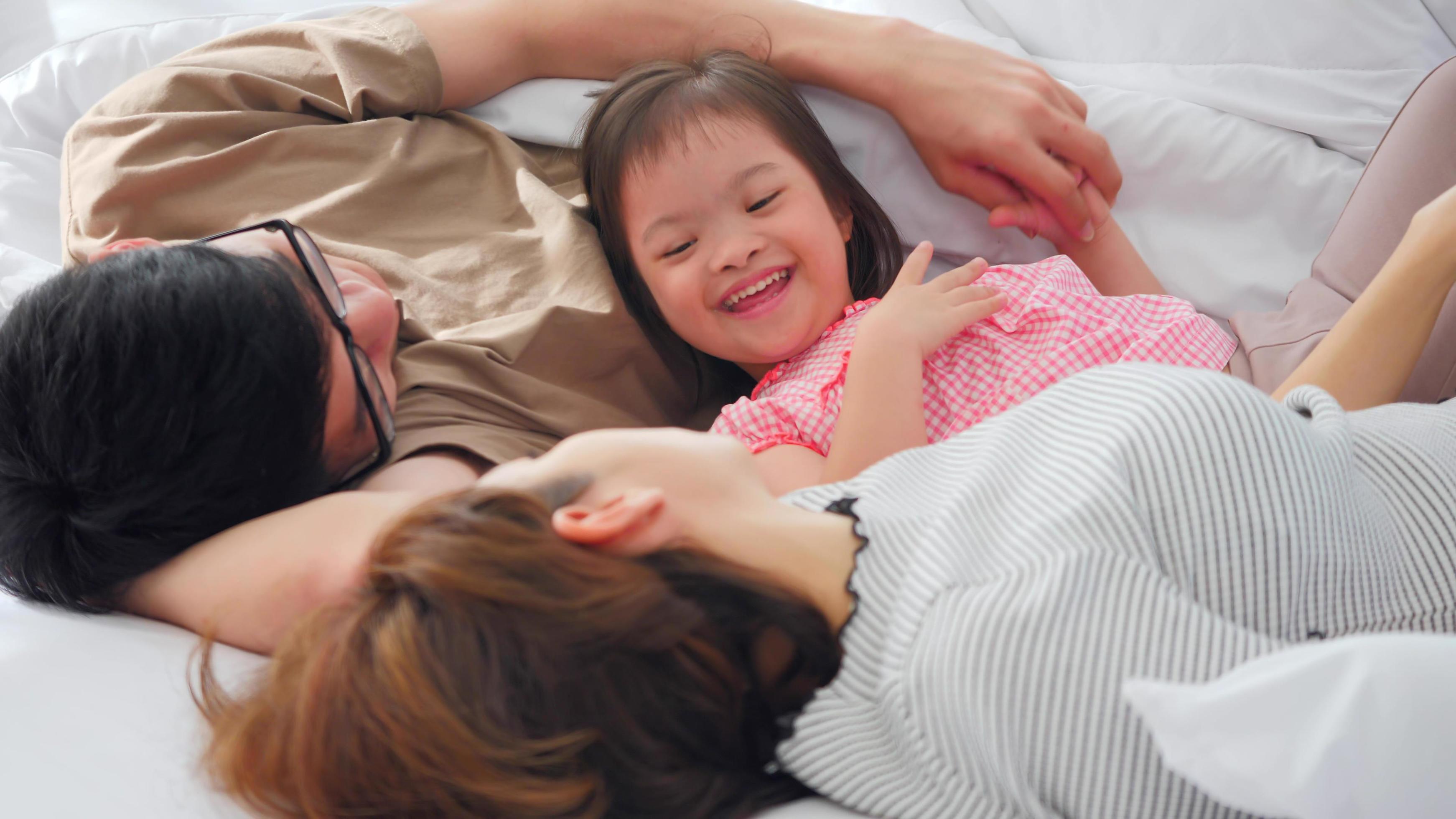 Happy family with mother, father and disabled daughter spending time together in bedroom. Stock Free