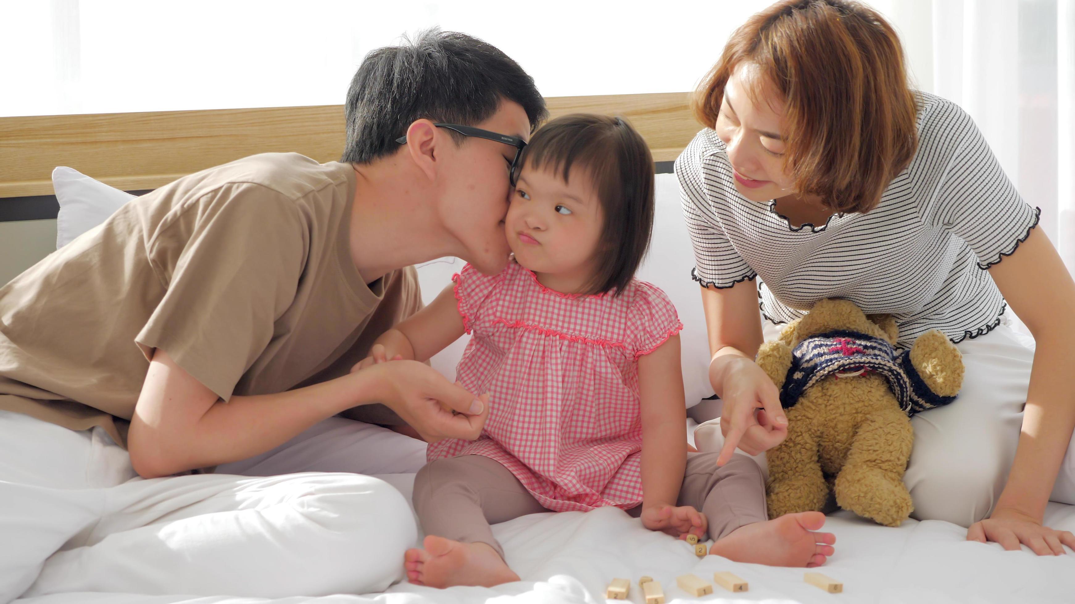 Happy family with mother, father and disabled daughter spending time together in bedroom. Stock Free