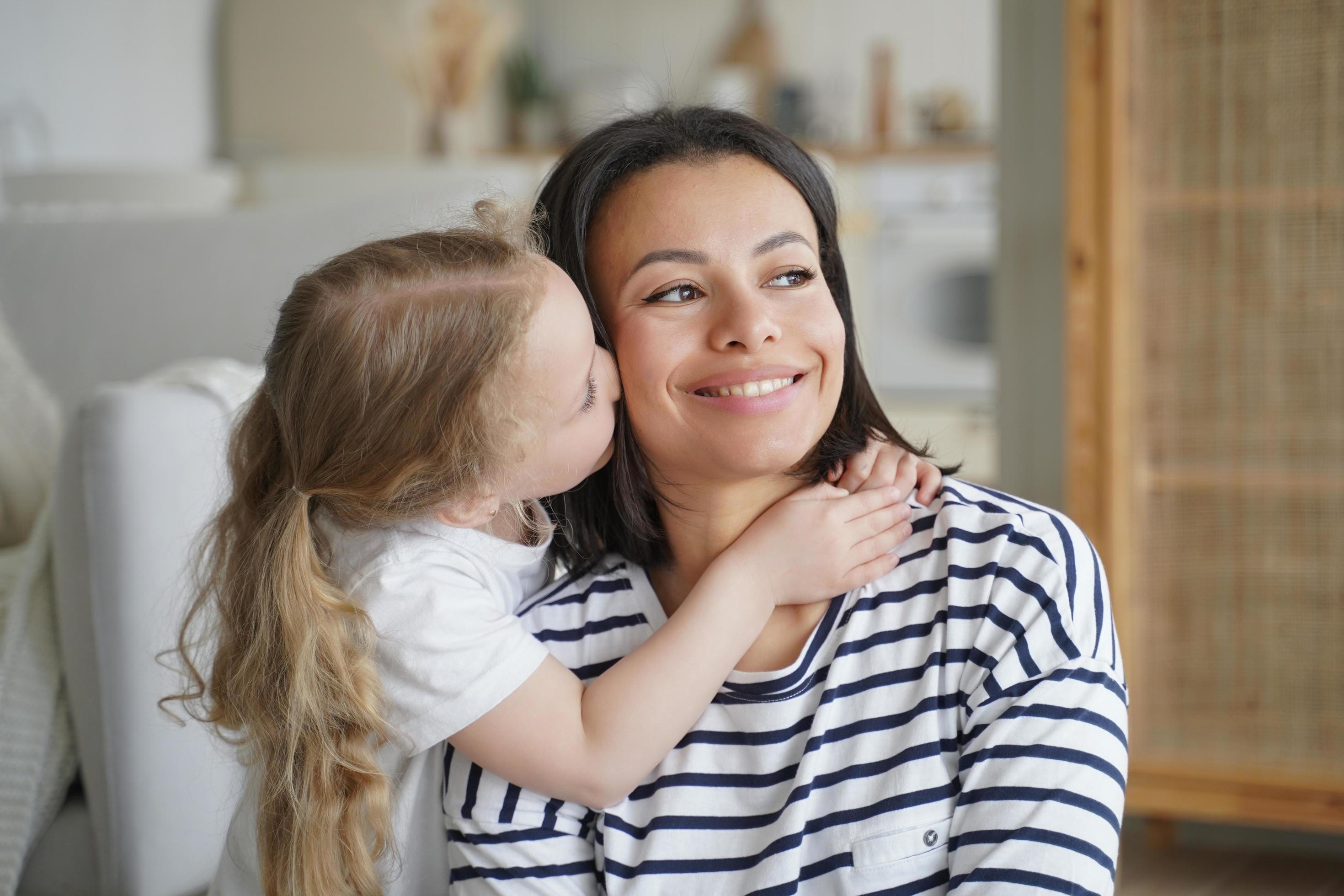 Portrait of family, kid hugs and kisses mom. Mother is smiling. Concept of affection and motherhood. Stock Free