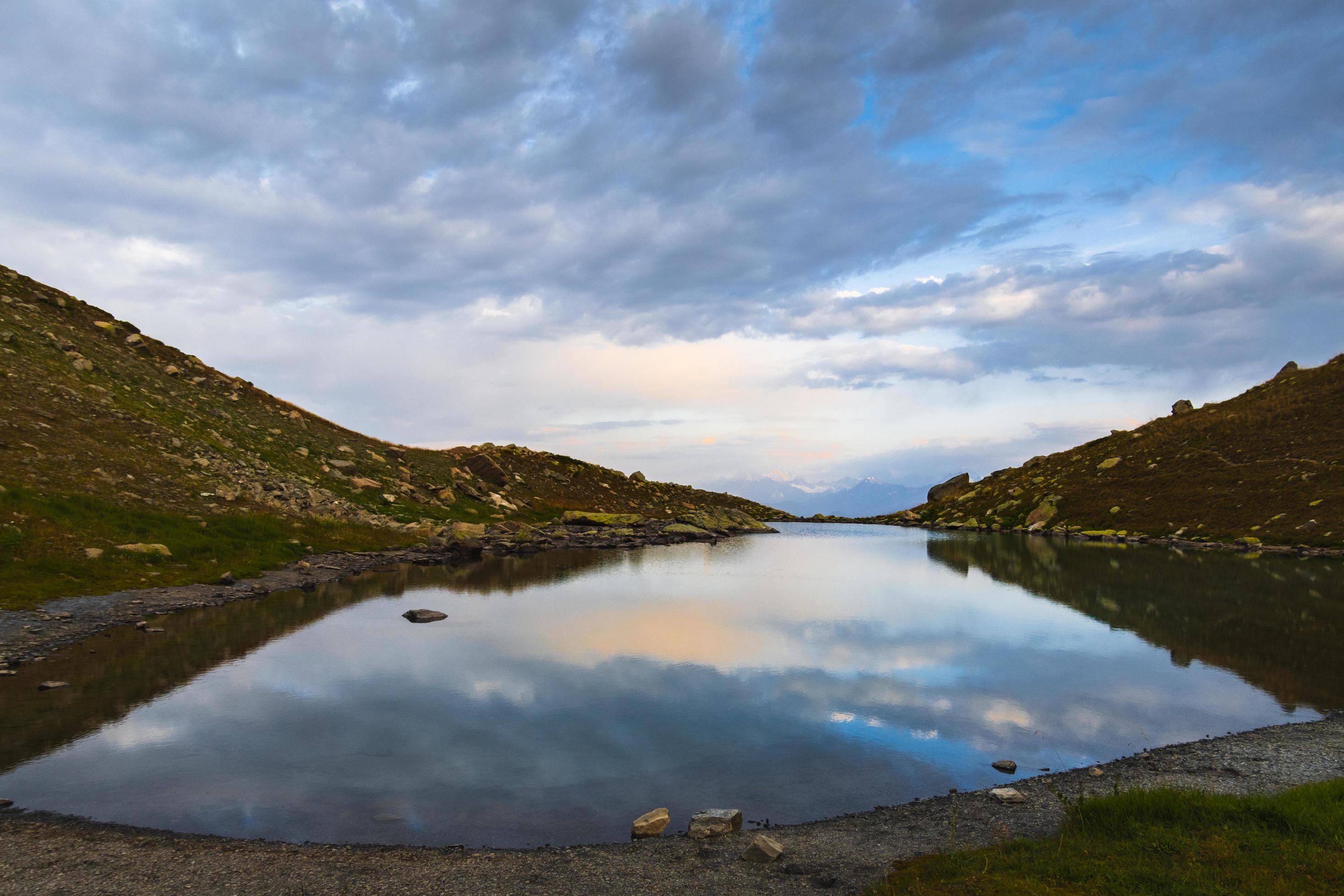 Aerial panning view Udziro lake panorama in autumn with tents by lake in rocky terrain outdoors Stock Free