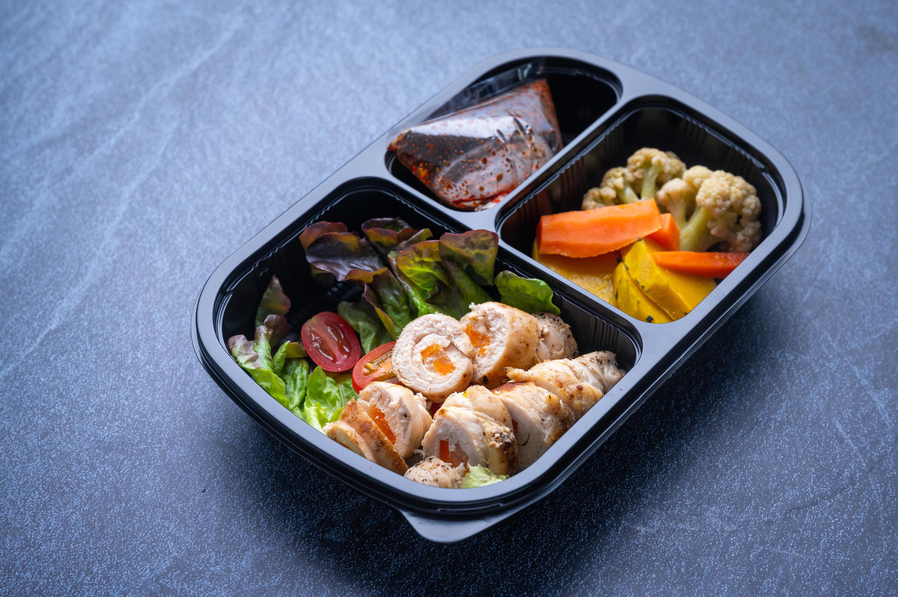 
									Sectioned plastic food container with salad, sliced meat, and vegetables Stock Free